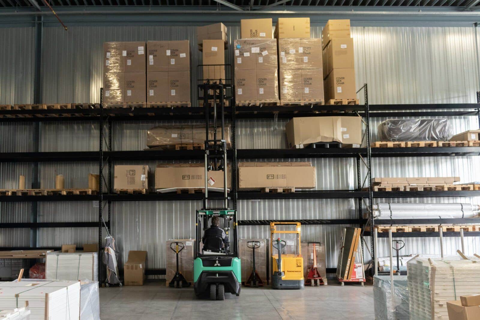 Magazijn met meubeldozen op stellingen en een heftruck, meubellogistiek door Bernardt VAD